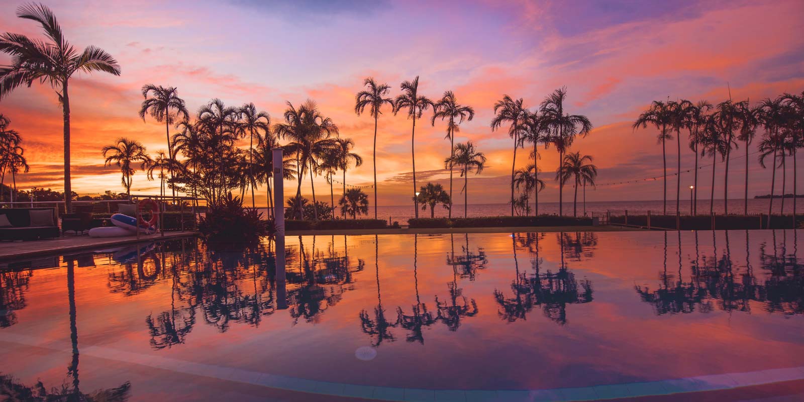 Sunset view from the infinity pool looking out to the beach and palm trees.